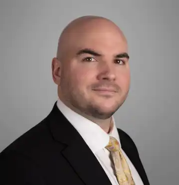 Dummit Fradin Criminal Defense Attorney Patrick Apple Bio Patrick Apple, criminal defense attorney and managing partner at Dummit Fradin in Greensboro, NC, wearing a black suit with a light patterned tie, looking confidently at the camera.