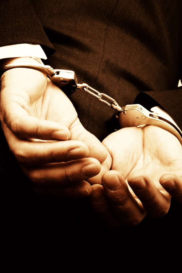 Navigating a DWI Arrest in Greensboro, NC What You Need to Know Close-up of a man in a suit with his hands cuffed behind his back, symbolizing arrest and legal consequences.