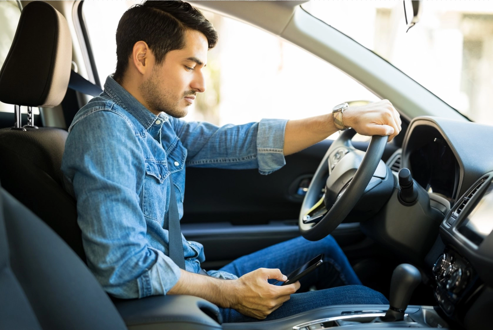 Man distracted by phone while driving in Greensboro, NC, demonstrating careless driving behavior that may be punishable under North Carolina law.
