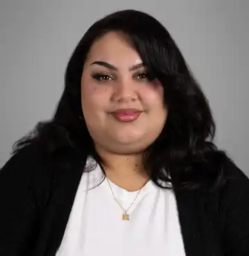 Mia Moreno Asistente legal Dummit Fradin Greensboro, Carolina del Norte BIO Mia Moreno, asistente legal de defensa penal en Dummit Fradin en Greensboro, Carolina del Norte, con suéter negro y blusa blanca, sonriendo suavemente a la cámara.